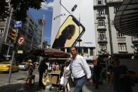 People walk past an advertising billboard at an upscale neighbourhood in Istanbul, Wednesday, Aug. 15, 2018. Turkey's President Recep Tayyip Erdogan, had said that his country will boycott U.S.-made electronic goods amid a diplomatic spat that has helped trigger a Turkish currency crisis. (AP Photo/Lefteris Pitarakis)