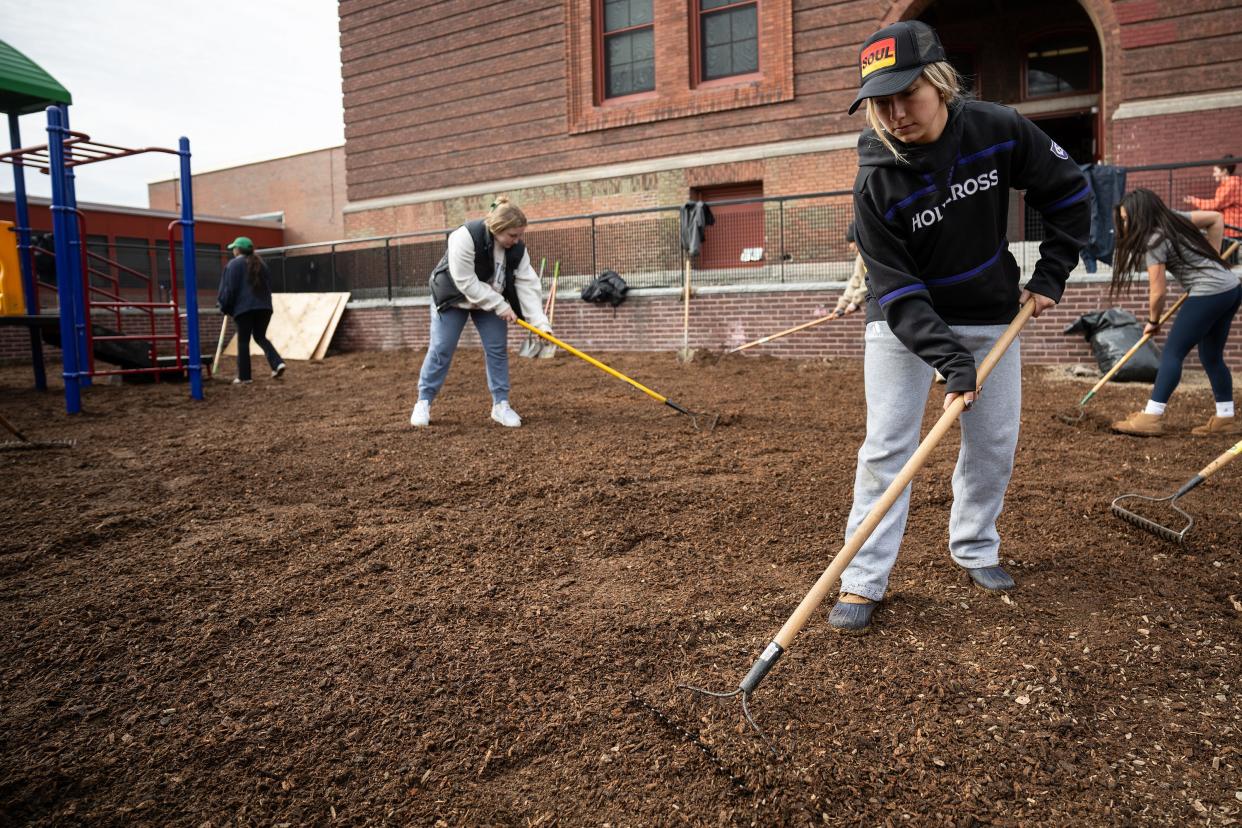 Kylie Hampton, a Holy Cross senior and member of the field hockey team, spreads mulch on the new playground volunteers erected at Union Hill Elementary School on Saturday.