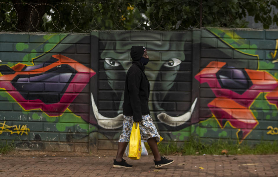 A woman wearing a face mask as a precaution against coronavirus outbreak, walks on the street in downtown Johannesburg, South Africa, Tuesday, Jan. 26, 2021. (AP Photo/Themba Hadebe)