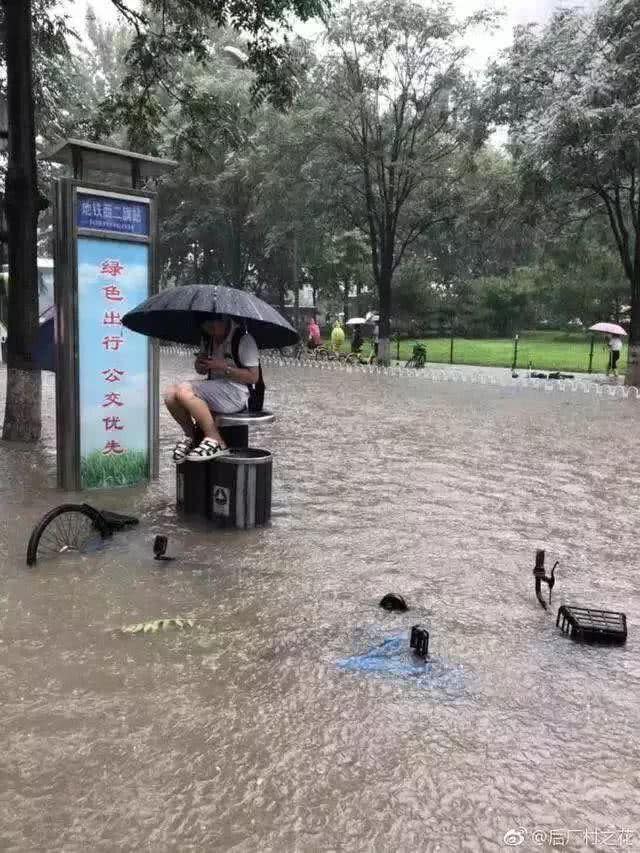 北京大雨，西二旗青年雨中淡定滑手機。（網路截圖）