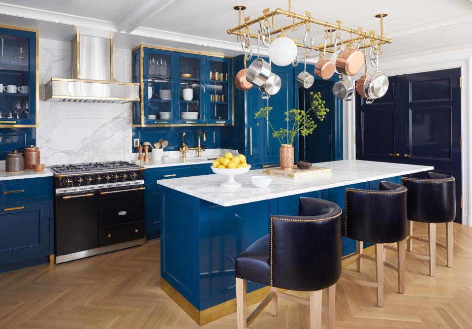 The kitchen of JJ and Chelsea Redick's Brooklyn duplex is lacquered in a custom Aegean blue from Fine Paints of Europe; polished bronze hardware frames the cabinetry. The matte black Lacanche stove features natural brass fittings.