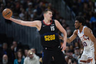 Denver Nuggets center Nikola Jokic holds the ball away from Phoenix Suns forward Thaddeus Young during the first half of an NBA basketball game Wednesday, March 27, 2024, in Denver. (AP Photo/David Zalubowski)