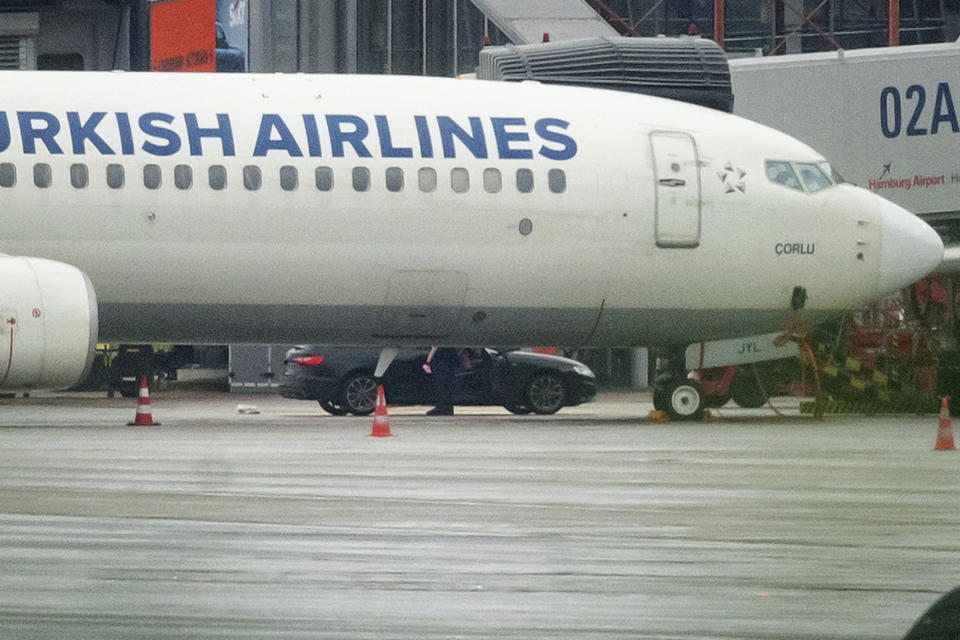 A man gets out of his vehicle near an airplane with his child in his arms at Hamburg Airport, Germany, Sunday Nov. 5, 2023. The hostage situation at Hamburg Airport ended Sunday afternoon, around 18 hours after a man drove his vehicle through the gates of the airport with his 4-year-old daughter inside, authorities said. The man was arrested and the girl appears to be unharmed. (Jonas Walzberg/dpa via AP)