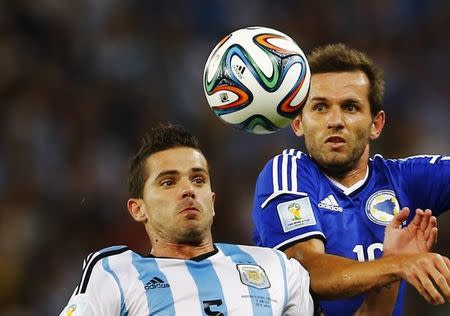 Bosnia's Zvjezdan Misimovic (R) jumps for the ball with Argentina's Fernando Gago during their 2014 World Cup Group F soccer match at the Maracana stadium in Rio de Janeiro June 15, 2014. REUTERS/Pilar Olivares