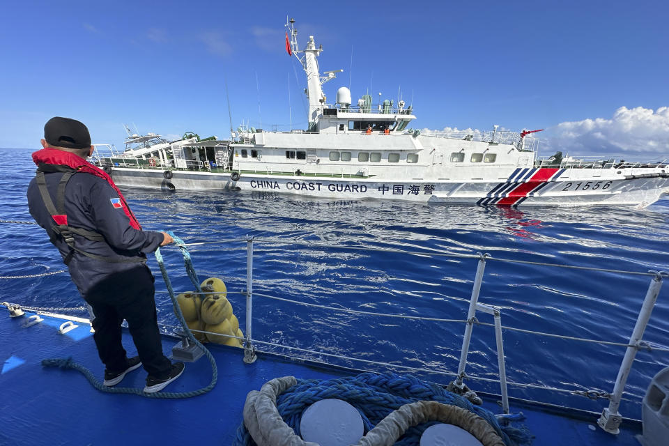 A Philippine Coast Guard member holds on a rubber fender as a Chinese coast guard vessel chases the Philippine coast guard vessel BRP Cabra while approaching Second Thomas Shoal, locally known as Ayungin Shoal, during a resupply mission at the disputed South China Sea on Friday Nov. 10, 2023. (AP Photo/Joeal Calupitan)