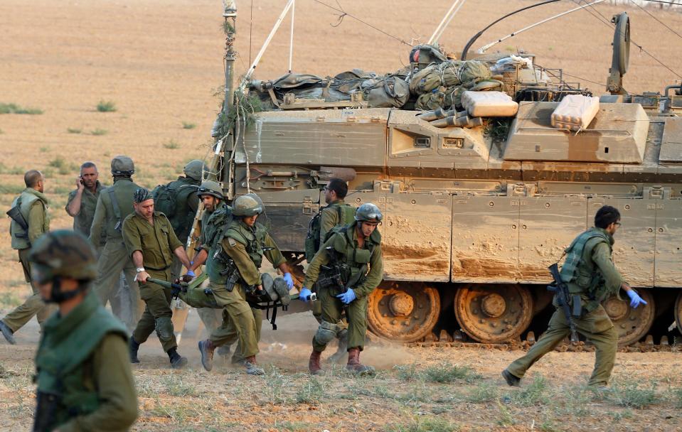 Israeli soldiers carry a comrade on a stretcher, who was wounded during an offensive in Gaza, outside northern Gaza July 20, 2014