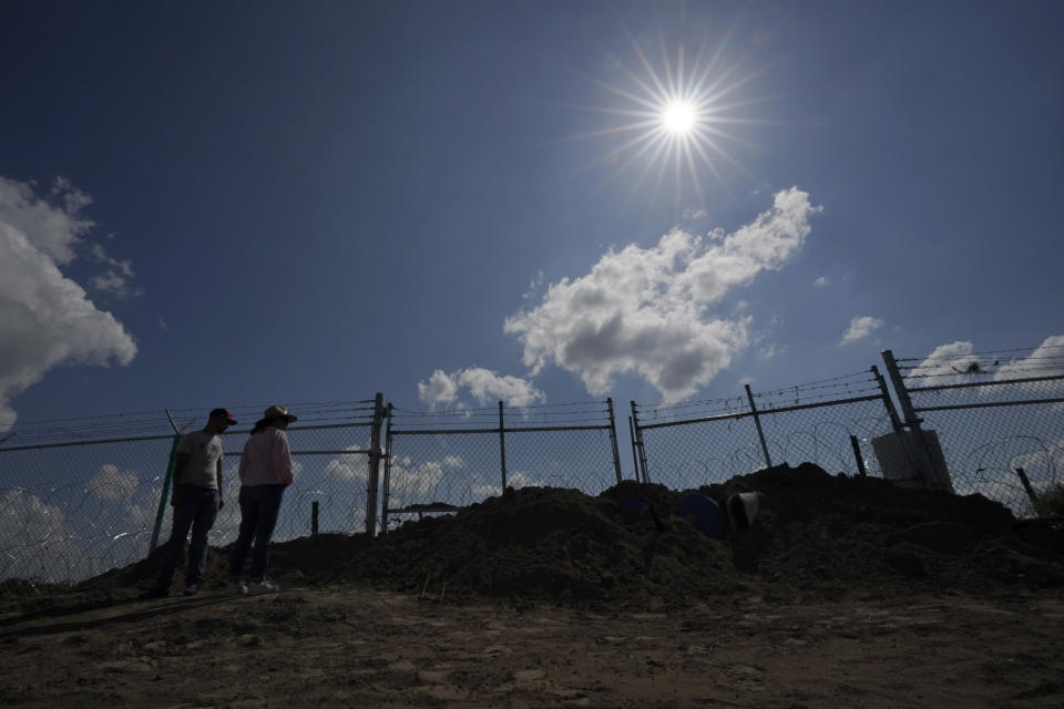 Magali Urbina, right, and her son Tony watch as the state installs large buoys to be used as a border barrier along the Rio Grande along her farm near Eagle Pass, Texas, Monday, July 7, 2023. Texas Republican Gov. Greg Abbott has escalated measures to keep migrants from entering the U.S. He's pushing legal boundaries along the border with Mexico to install razor wire, deploy massive buoys on the Rio Grande and bulldozing border islands in the river. (AP Photo/Eric Gay)