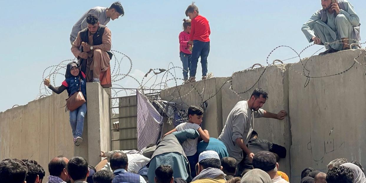 Afghanis climbing over the Kabul Airport fence in Afghanistan