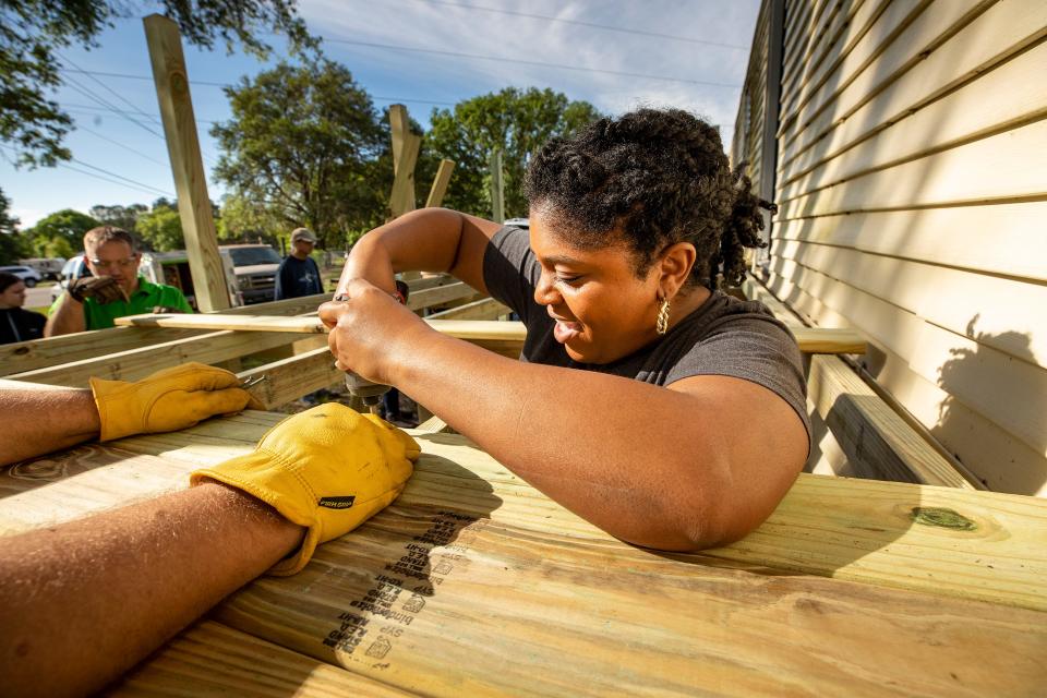 Shawna Funderburk, a volunteer from Publix, uses a drill to screw deck boards into place in front of the Persaud family's mobile home in the Kathleen area. Habitat for Humanity is supporting the renovation of the structure.