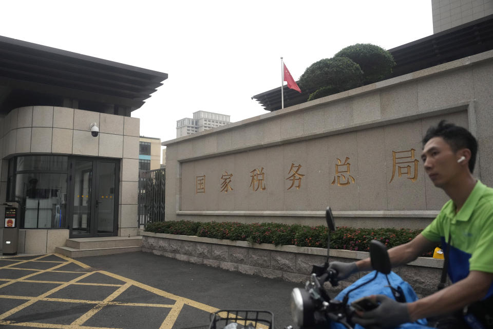 A man on an electric bike passes by the State Administration of Taxation in Beijing, Friday, Aug. 2, 2024. (AP Photo/Ng Han Guan)