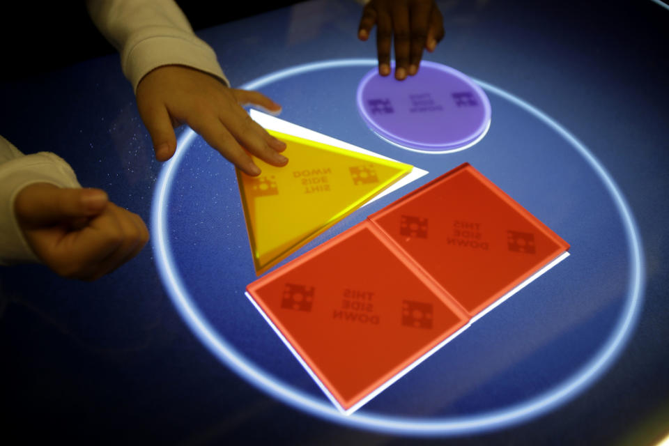 Visitors to the new National Museum of Mathematics try out an interactive exhibit in New York, Monday, Dec. 17, 2012. The museum is aimed at kids aged 8 to 13, and curators have given the place a playground feel. The 40 exhibits include a "wall of fire" made up of laser lights that teaches kids about geometry and a square-wheeled tricycle that still manages to produce a smooth ride thanks to a wavy track. (AP Photo/Seth Wenig)