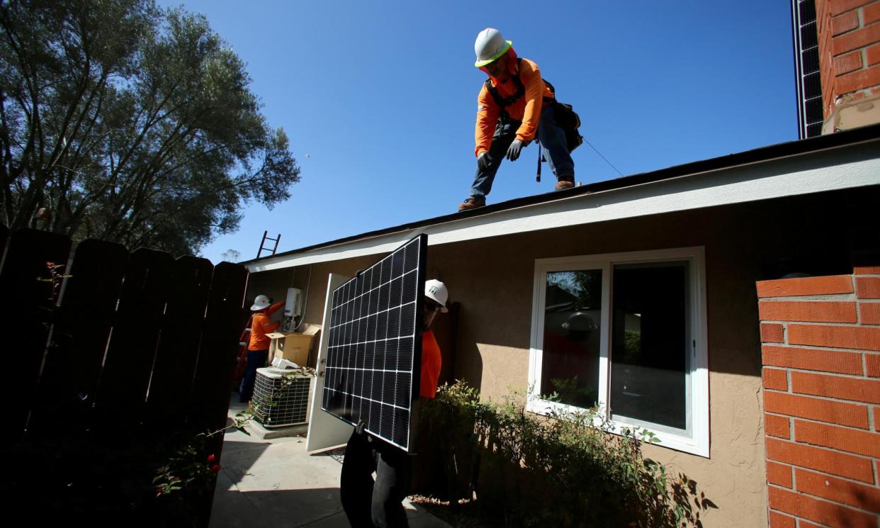 <span>Workers lift a solar panel on to a roof during a residential solar installation in Scripps Ranch, San Diego, California.</span><span>Photograph: Mike Blake/Reuters</span>