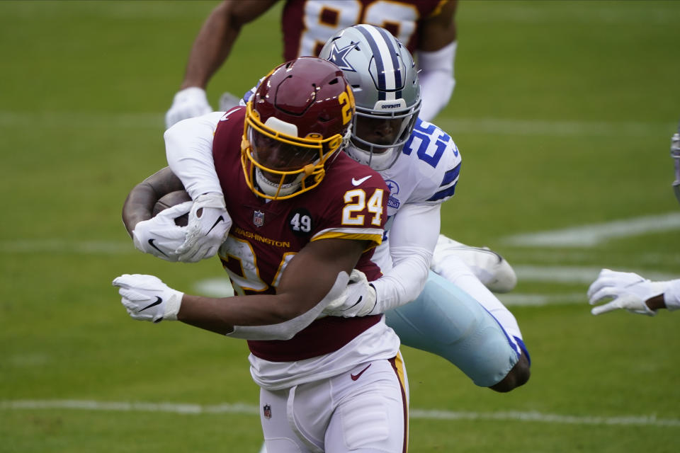 Washington Football Team running back Antonio Gibson (24) is tackled by Dallas Cowboys free safety Xavier Woods (25) in the first half of an NFL football game, Sunday, Oct. 25, 2020, in Landover, Md. (AP Photo/Susan Walsh)