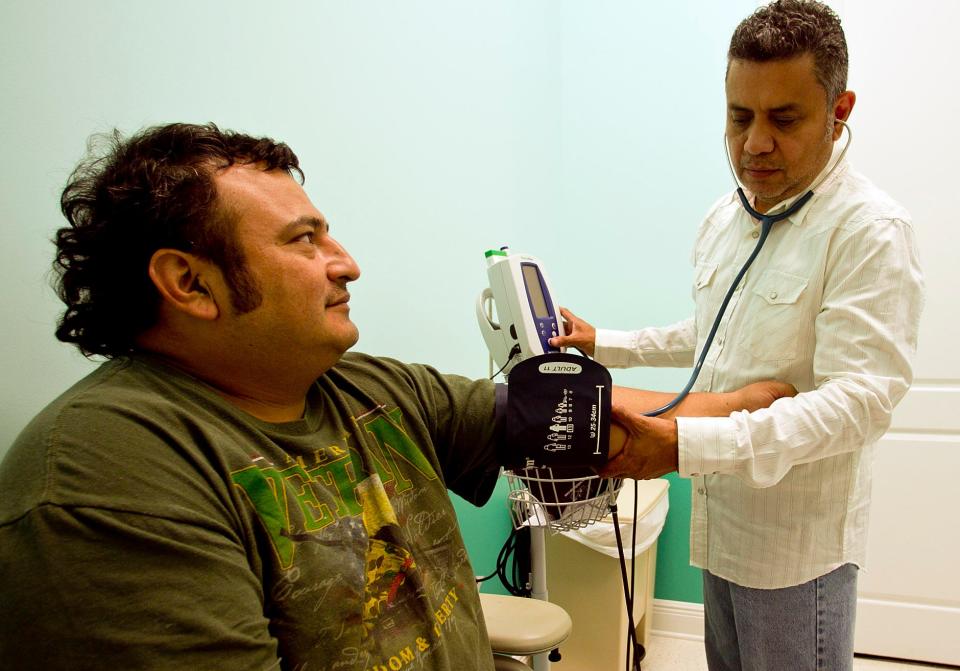 Rafael Carcache checks the blood pressure of a Hispanic man at the Slocomb Health Clinic.