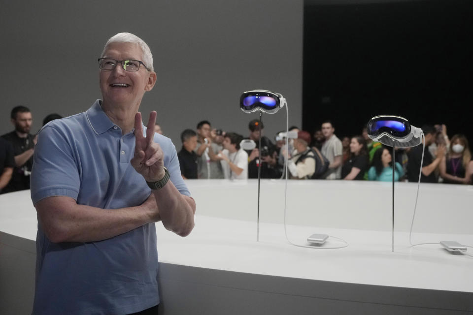 Apple CEO Tim Cook poses for photos in front of the company's headsets in a showroom.