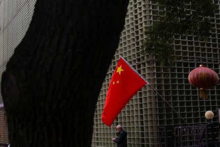 A man stands underneath a Chinese national flag in a hutong alley in the old part of Beijing as the capital prepares for the 19th National Congress of the Communist Party of China, October 14, 2017. REUTERS/Thomas Peter