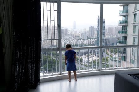 An Zhizhong, one of An Hui's and Ye Jianbin's three sons, stands next to a window at home in Shenzhen, Guangdong province, China September 17, 2018. An and Ye are fathers of triplets who were conceived with the help of a German egg donor. REUTERS/Jason Lee