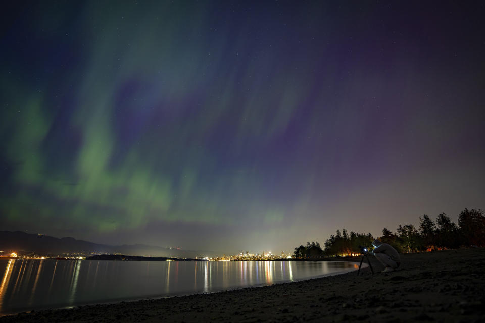A person takes a photo of Aurora Borealis or the Northern Lights in Vancouver, B.C., Saturday, May. 11, 2024. Brilliant purple, green, yellow and pink hues of the Northern Lights were reported worldwide, with sightings in Germany, Switzerland, London, and the United States and Canada. (Ethan Cairns /The Canadian Press via AP)