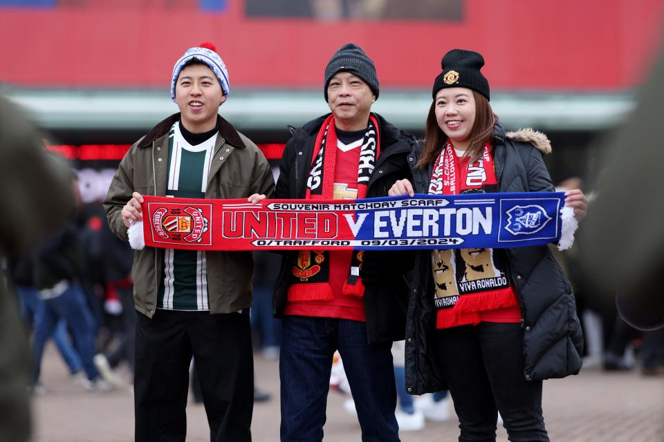 Fans outside Old Trafford pose with a half-and-half scarf (Getty Images)