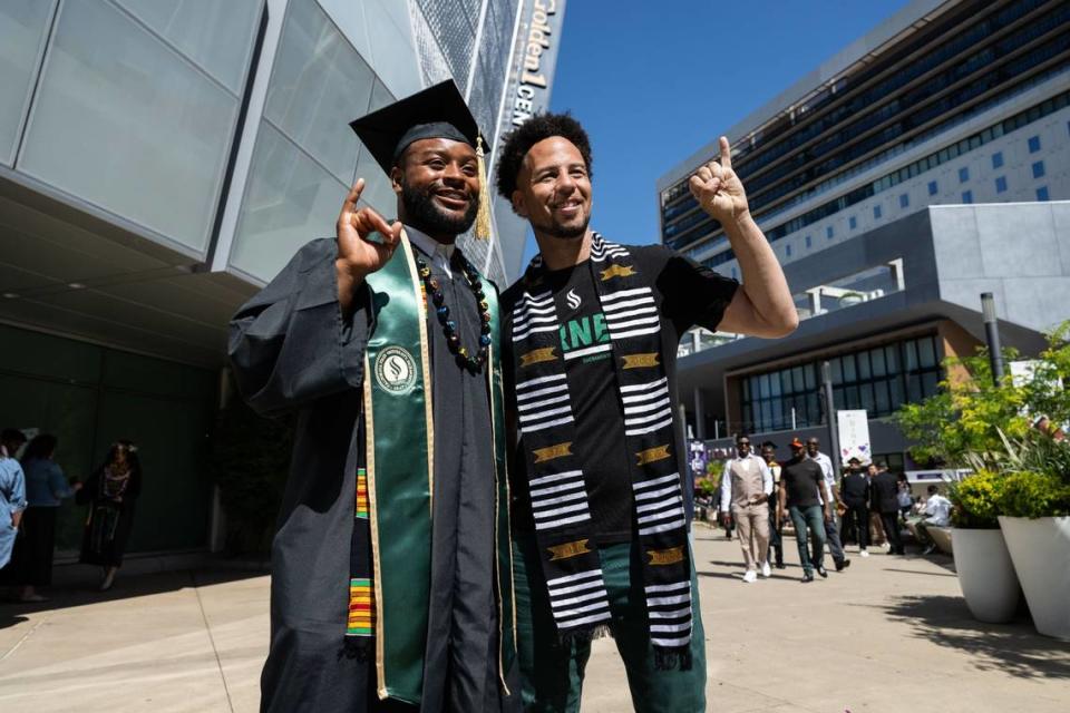 Sacramento State graduate Paul Lawrence Dunbar Banks makes the “stingers up” sign with university President Luke Wood for a photo after the commencement ceremony at Golden 1 Center on Friday.