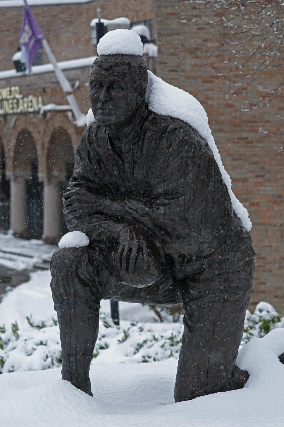 The statue of former Washington NCAA college football coach Jim Owens wears a coating of snow, Saturday, Feb. 13, 2021, in Seattle. Winter weather was expected to continue through the weekend in the region.(AP Photo/Ted S. Warren)