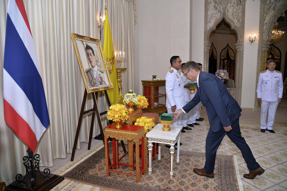 In this photo released by Government Spokesman Office, Richard Harris, an Australian member of the Thai cave rescue team, receives the Member of the Most Admirable Order of the Direkgunabhorn in front of a portrait of Thailand's King Maha Vajiralongkorn Bodindradebayavarangkun during the royal decoration ceremony at the Royal Thai Government House in Bangkok, Thailand, Friday, April 19, 2019. Two Australian doctors, Harris and Craig Challen, received royal honors for helping rescue the Wild Boars soccer team from a flooded cave (Government Spokesman Office via AP)