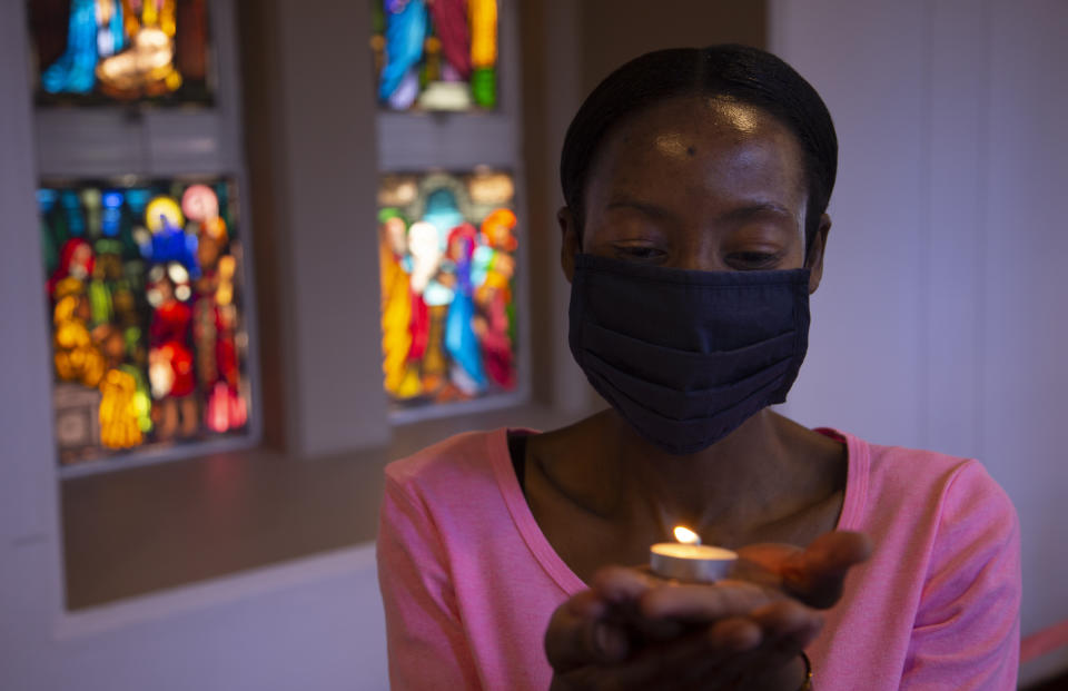 A worshipper wearing a face mask, holds a lit candle prior to a morning Christmas Mass at the Rosebank Catholic Church in Johannesburg, Friday, Dec. 25, 2020. (AP Photo/Denis Farrell)