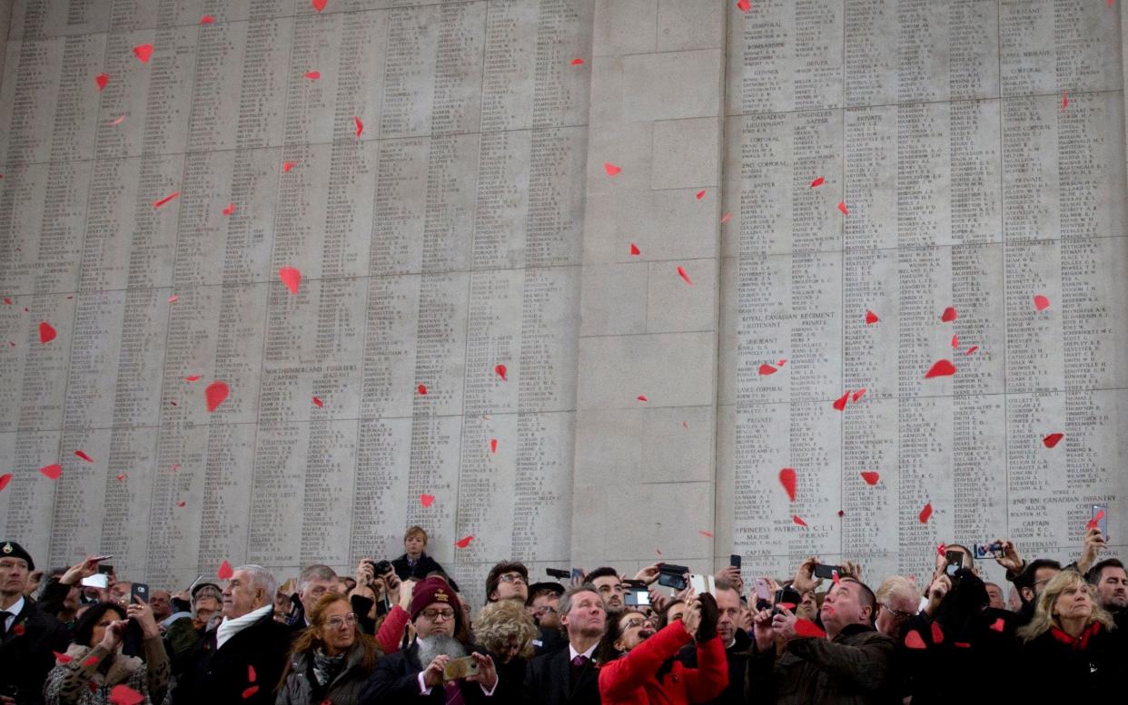 People watch as red paper poppies fall from the roof at the Menin Gate during an Armistice ceremony in - AP