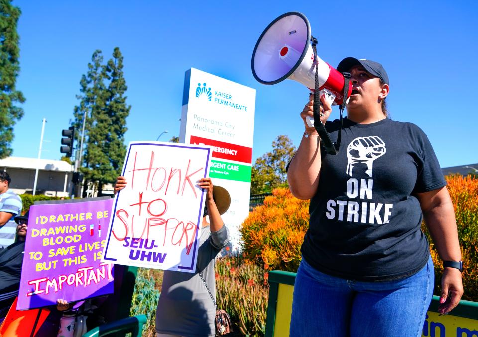 Jovanna Segura uses a bullhorn to lead chants with striking health care workers in front of Kaiser Permanente Medical Center in Panorama City, Calif. on Wednesday, Oct. 4, 2023.