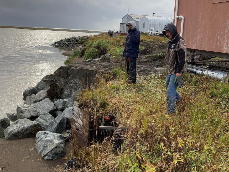 Reppi Swan Sr. and Joe Swan Jr. inspect an eroded property they shored up during a storm. Janet Mitchell