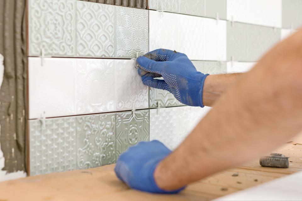 Installing ceramic tiles in a kitchen backsplash involves placing appropriately sized spacers.