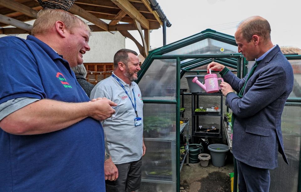 Britain's Prince William, Duke of Cambridge (R) holds a pink watering can during his visit to Brighter Futures, a consortium of eight local groups which encourage loal people to participate in community activities, in Rhyl, Denbighshire, Wales on May 6, 2021. (Photo by Peter Byrne / POOL / AFP) (Photo by PETER BYRNE/POOL/AFP via Getty Images)