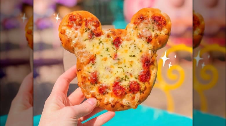 Mickey Mouse-shaped pizza in hand