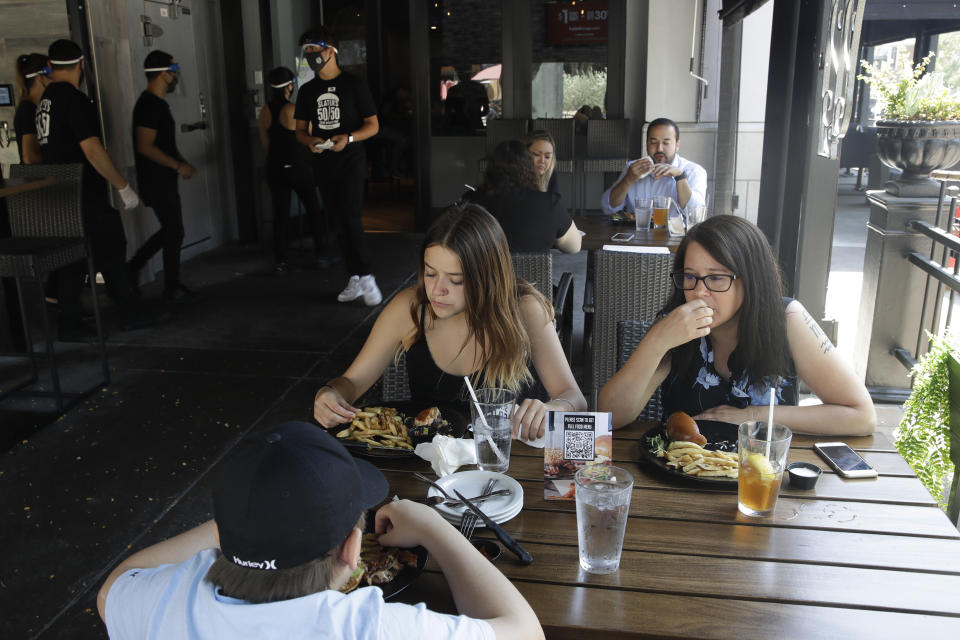 Patrons eat lunch at Slater's 50/50 Wednesday, July 1, 2020, in Santa Clarita, Calif. California Gov. Gavin Newsom has ordered a three-week closure of bars, indoor dining and indoor operations of several other types of businesses in various counties, including Los Angeles, as the state deals with increasing coronavirus cases and hospitalizations. (AP Photo/Marcio Jose Sanchez)