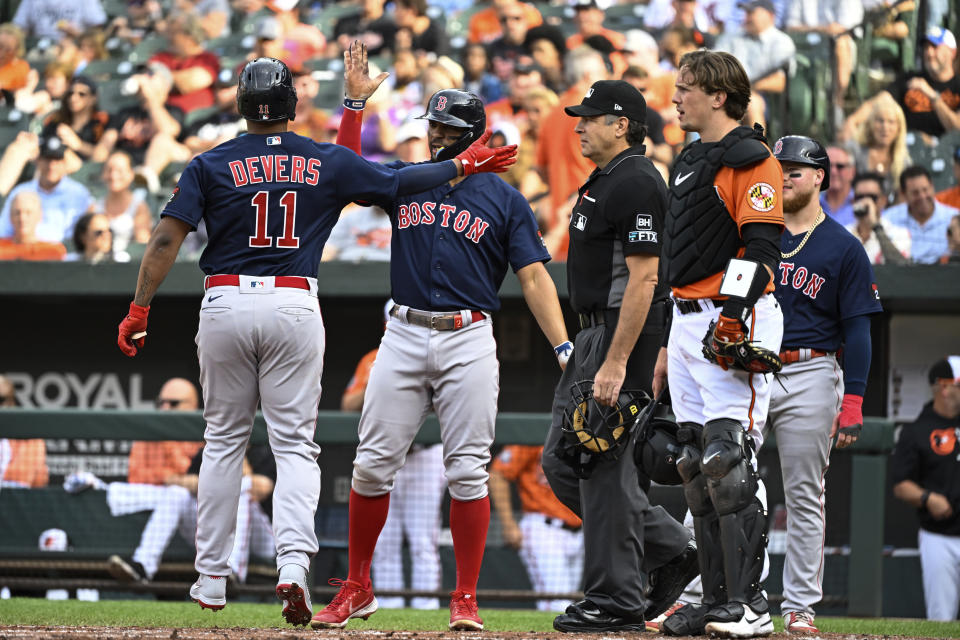 Boston Red Sox' Rafael Devers (11) is greeted at home plate by teammates after hitting a grand slam home run against Baltimore Orioles starting pitcher Jordan Lyles which scored Tommy Pham, Alex Verdugo, Xander Bogaerts during the first inning of a baseball game, Saturday, Sept. 10, 2022, in Baltimore. (AP Photo/Terrance Williams)