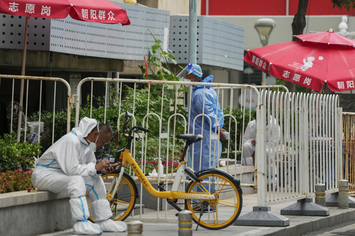 Workers in protective gear on duty watch at barricaded neighborhood that has been locked down as part of COVID-19 controls in Beijing, Monday, June 13, 2022. China's capital has put school online in one of its major districts amid a new COVID-19 outbreak linked to a nightclub, while life has yet to return to normal in Shanghai despite the lifting of a more than two month-long lockdown. (AP Photo/Andy Wong)