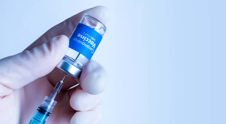 A hand holding a Covid-19 vaccine vial and a needle.