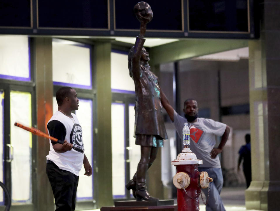 Two men stand by the Mary Tyler Moore statue on Nicollet Mall following a night of unrest in Minneapolis, Thursday, Aug. 27, 2020. An emergency curfew expired and downtown Minneapolis was calm Thursday morning after a night of unrest that broke out following what authorities said was misinformation about the suicide of a Black homicide suspect. (David Joles/Star Tribune via AP)