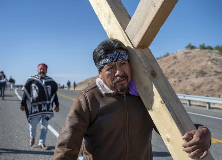 Jaime Gonzales, from Rio Rancho, and other family members carry a 150-pound cross along Santa Fe County Road 98 on their way to Santuario de Chimayo, Friday, April 7, 2023. Thousands of people made the Good Friday pilgrimage to the sacred Northern New Mexico church. (Eddie Moore/The Albuquerque Journal via AP)