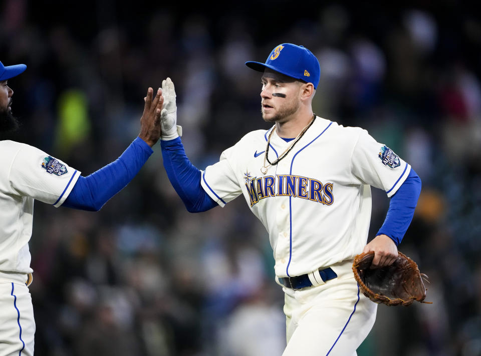 Seattle Mariners' Jarred Kelenic, right, high-fives teammate Teoscar Hernandez, left, as they celebrate a 1-0 win over the Colorado Rockies in a baseball game, Sunday, April 16, 2023, in Seattle. Kelenic drove in the only run of the game, an RBI single in the sixth inning to score Ty France. (AP Photo/Lindsey Wasson)