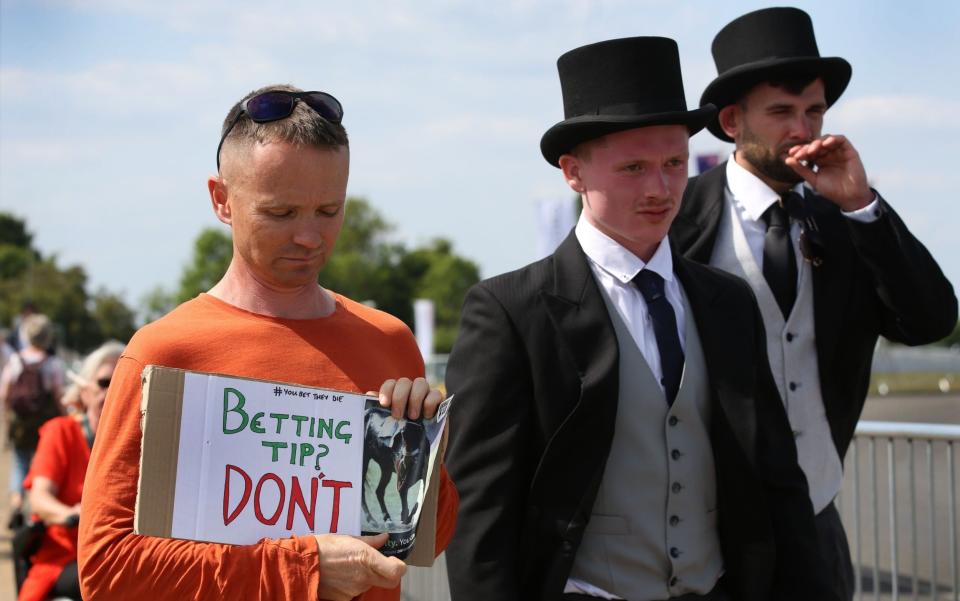 Animal Rising supporters protest with signs outside the main grandstand while race goers with top hats go past on June 3, 2023 in Epsom - Getty Images/Martin Pope