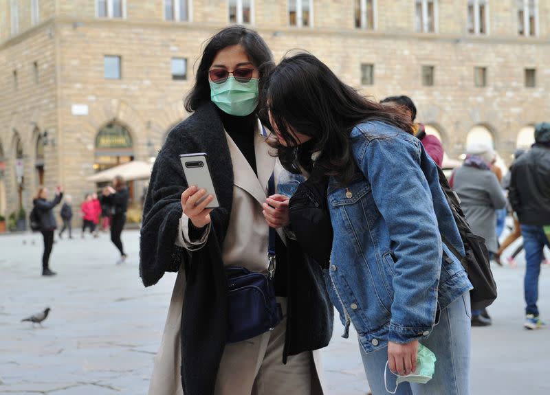 FOTO DE ARCHIVO: Dos mujeres con máscaras protectoras miran un teléfono en Florencia