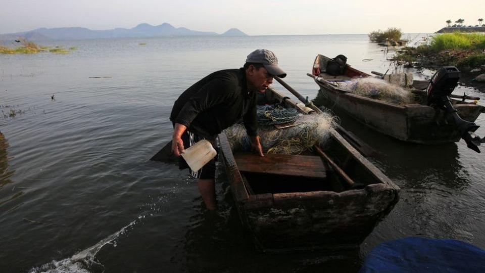 Pescador sacando agua de su barco de pesca