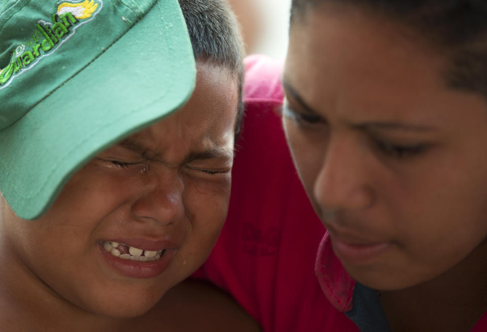 FILE - In this Oct. 26, 2018 file photo, a mother comforts her son as blisters on his feet are treated by Mexican Red Cross volunteers, in Arriaga, Chiapas state, Mexico, as the U.S.-bound migrant caravan stops for the night. Many in the caravan have now covered more than 800 miles since setting out from Honduras on Oct. 13, hitching rides when possible, and face another more than 800-mile trek to the nearest U.S. border crossing. (AP Photo/Rebecca Blackwell, File)