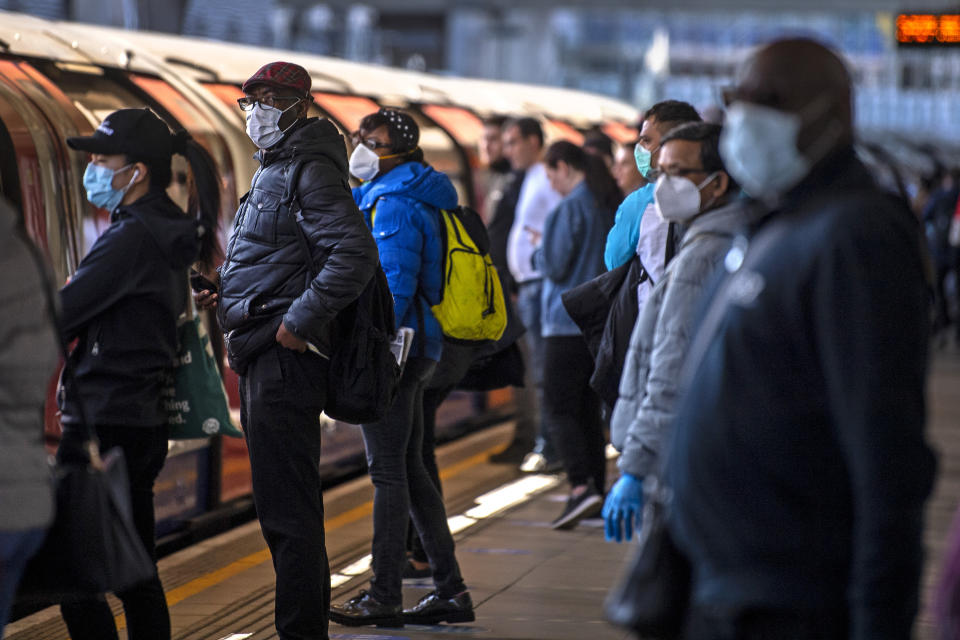 Passengers wearing face masks on a platform at Canning Town underground station in London.