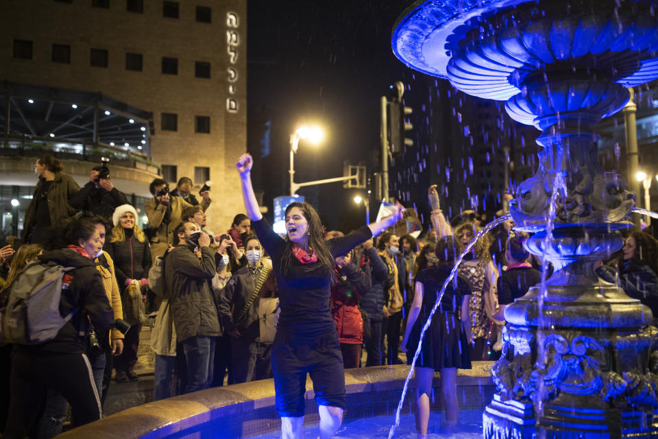 A woman dances in a fountain in Paris Square, where protesters gathered outside of Israeli Prime Minister Benjamin Netanyahu's official residence in Jerusalem, Saturday, Jan. 16, 2021. (AP Photo/Maya Alleruzzo)