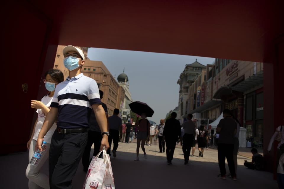 People wearing face masks to protect against the new coronavirus walk at a government event aiming to stimulate consumer demand and consumption in Beijing, Saturday, June 6, 2020. China's capital is lowering its emergency response level to the second-lowest starting Saturday for the coronavirus pandemic. That will lift most restrictions on people traveling to Beijing from Wuhan and surrounding Hubei province, where the virus first appeared late last year. (AP Photo/Mark Schiefelbein)