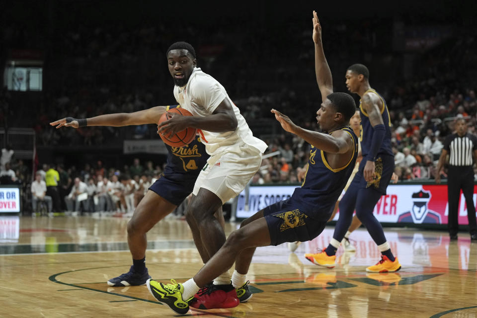 Notre Dame guard Markus Burton, right, falls after contact from Miami guard Bensley Joseph (4) during the first half of an NCAA college basketball game, Saturday, Dec. 2, 2023, in Coral Gables, Fla. (AP Photo/Jim Rassol)