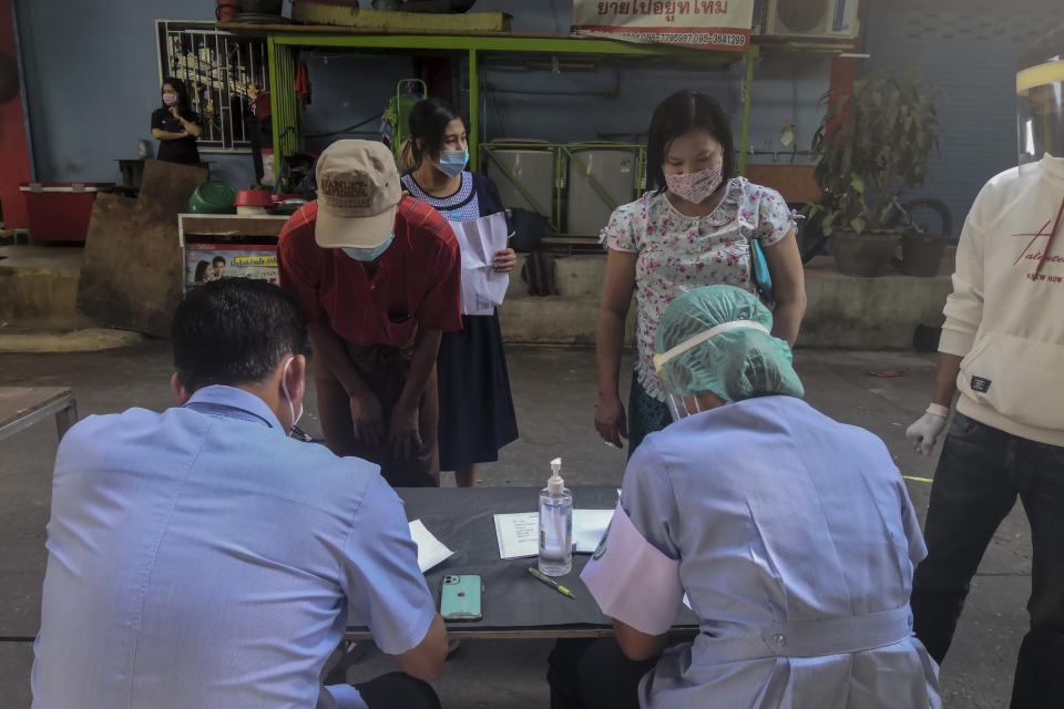 Health workers record migrant workers ahead of collecting nasal swab samples from them to test for COVID-19 in Samut Sakhon, south of Bangkok, Thailand, Sunday, Dec. 20, 2020. Thailand on Sunday reported a few new local infections, a day after identifying more than 500 cases south of Bangkok in a country that had largely brought the pandemic under control. (AP Photo/ Chalida Ekvitthayavechnukul)