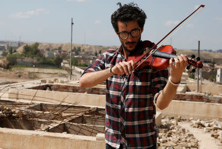 Ameen Mukdad, un violinista de Mosul que vivió bajo el régimen de Estado Islámico por dos años y medio y sufrió la destrucción de sus instrumentos musicales, realiza un pequeño concierto en el santuario de Nabi Yunus en el este de Mosul, Irak, 19 de abril de 2017. En medio de las ruinas bombardeadas de un antiguo lugar venerado por musulmanes y cristianos en Mosul, el violinista iraquí Ameen Mukdad realizó el miércoles un pequeño concierto en la ciudad de la que huyó obligado por milicianos de Estado Islámico. REUTERS/Muhammad Hamed